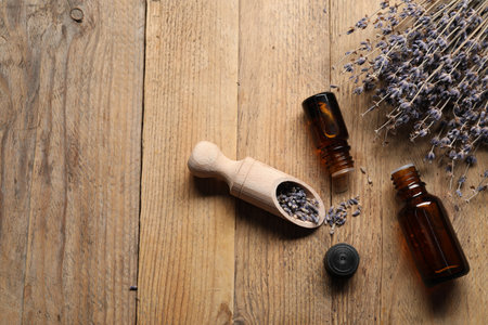 Natural essential oil and lavender flowers on wooden background, flat lay. Space for textの写真素材