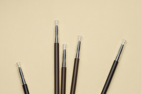 Automatic eyebrow pencils on beige background, flat layの写真素材