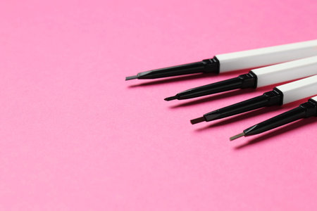 Twist up eyebrow pencils on bright pink background, closeup. Space for textの写真素材