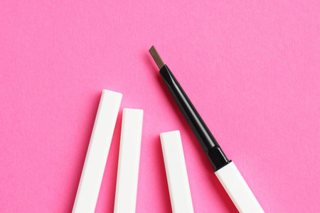 Twist up eyebrow pencils on bright pink background, flat layの写真素材