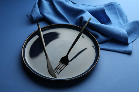 Stylish plate, cutlery and napkin on blue background, closeupの写真素材
