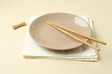 Stylish plate, chopsticks and napkin on beige background, closeupの写真素材