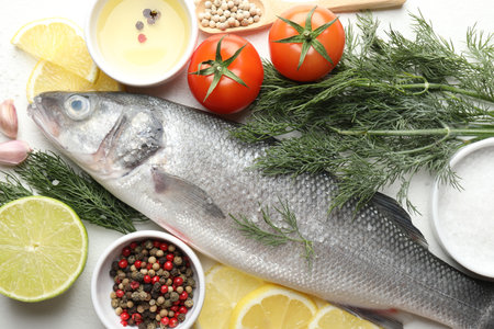 Fresh raw seabass with spices on white table, flat lay. Fish and seafood delicacies