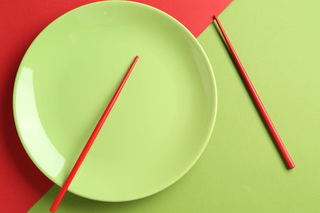 Stylish plate and chopsticks on color background, flat layの写真素材