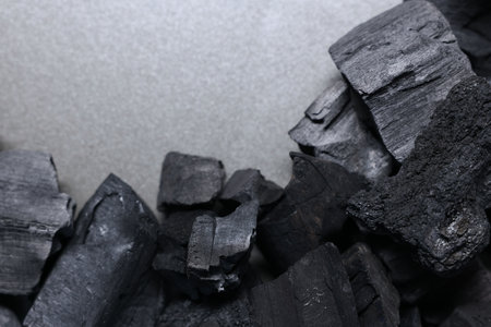 Pieces of black coals on grey table, top view. Space for textの写真素材