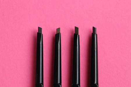 Twist up eyebrow pencils on bright pink background, flat layの写真素材