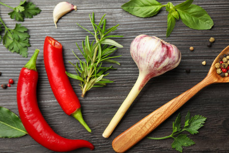 Different aromatic herbs, products and spoon with peppercorns on dark wooden table, flat layの写真素材