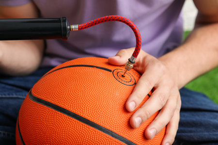 Man inflating basketball ball with manual air pump indoors, closeupの写真素材