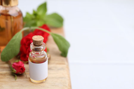 Bottles of essential oils, red roses and herbs on table, closeup. Space for textの写真素材