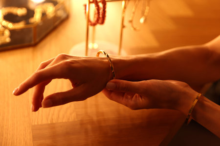 Woman wearing beautiful bracelet while getting ready at dressing table indoors, closeup