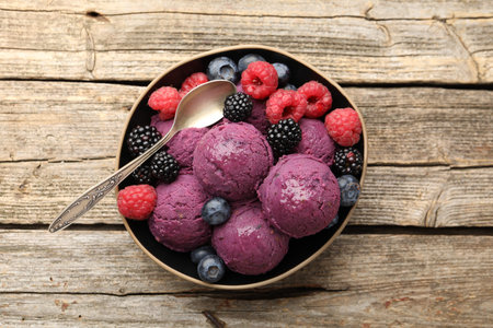Delicious sorbet and fresh berries in bowl on wooden table, top view
