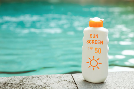 Sunscreen in bottle on swimming pool edge. Sun protection productの写真素材