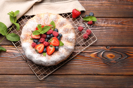 Tasty Bundt cake with powdered sugar and berries on wooden table, flat lay. Space for textの写真素材