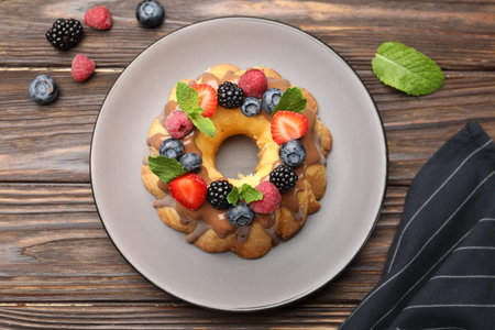 Tasty Bundt cake with berries, chocolate and mint on wooden table, top viewの写真素材