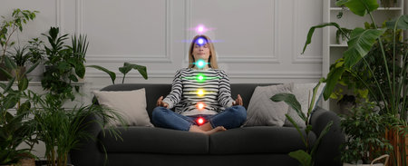 Woman meditating in Lotus pose at home. Rainbow lights representing chakras
