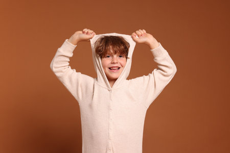 Cute little boy in pajamas on brown backgroundの写真素材