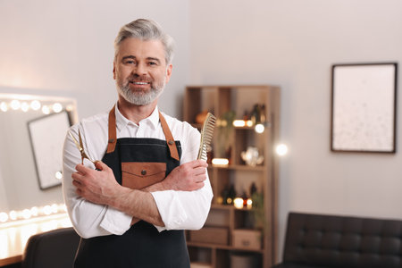 Smiling hairdresser with scissors and comb in beauty salon, space for textの写真素材