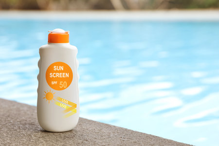 Sunscreen in bottle on swimming pool edge. Sun protection productの写真素材