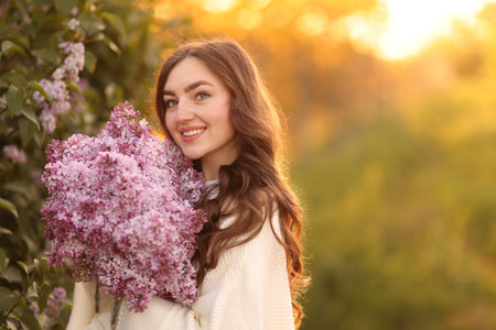 Smiling woman with bouquet of lilac flowers outdoors in morning. Space for text