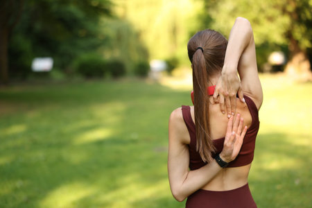 Sportswoman doing morning exercise in park, back view. Space for text
