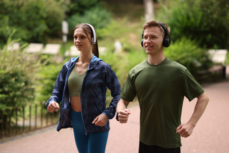 Happy couple in headphones running in park. Morning exerciseの写真素材