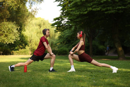 Happy couple in headphones doing morning exercises in parkの写真素材