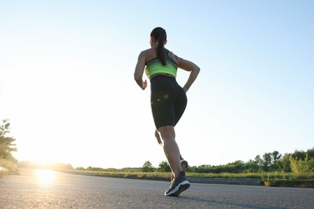 Woman in sportswear running on road outdoors, low angle view