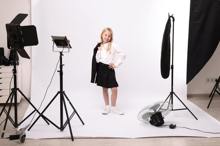 Little girl on white background in photo studio with professional equipmentの写真素材