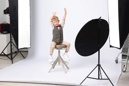 Little boy on white background in photo studio with professional equipmentの写真素材