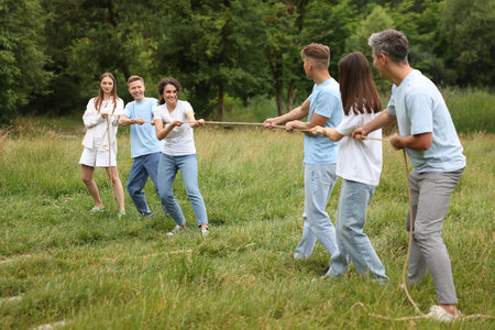 Team building. Group of happy people playing tug of war with rope outdoorsの写真素材