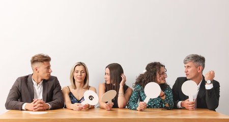 Panel of judges consulting at table against light grey backgroundの写真素材