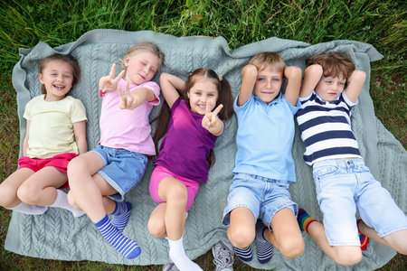 Happy children lying on blanket in nature, top view
