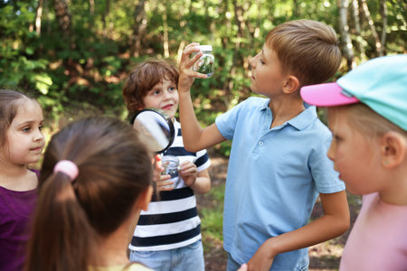 Children with jars and magnifying glass in nature