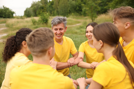 Team building. Group of happy people joining hands outdoorsの写真素材