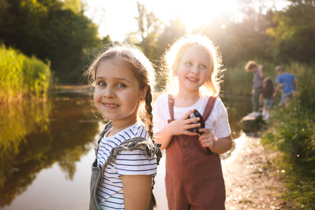 Children spending time in nature. Cute little girls by lake, selective focusの写真素材