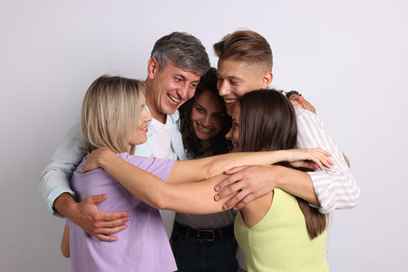 Group of happy friends hugging on grey background