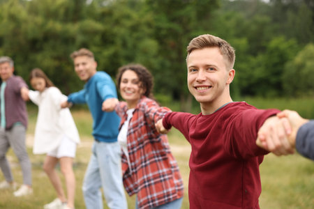 Team building. Group of happy people holding hands outdoors, selective focus