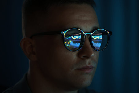 Young man wearing glasses with reflection on dark background, closeup