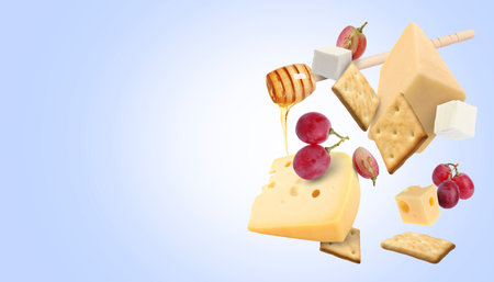 Cheese board products in air on blue gradient background. Different types of cheese, grapes, crackers and honeyの写真素材