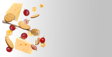 Cheese, grapes, crackers and honey in air on grey gradient background. Tasty appetizers for cheese...