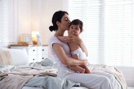 Mother with her cute little baby on bed indoorsの写真素材