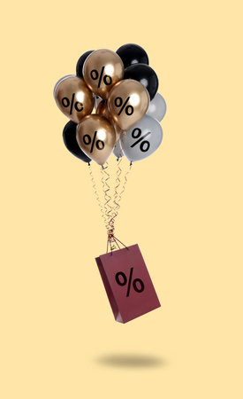 Shopping bag and balloons with percent signs in air against beige background
