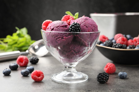 Delicious sorbet with fresh berries and mint in dessert bowl on grey textured table against dark...