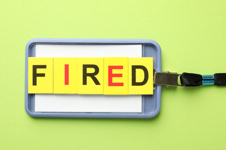 Dismissal. Word fired and badge on green background, top view