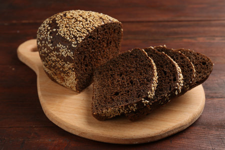 Pieces of fresh rye bread with seeds on wooden table, closeup
