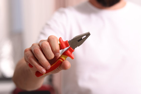 Closeup view of man with pliers indoors