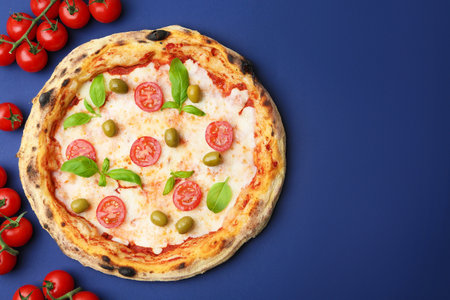 Delicious pizza and fresh tomatoes on blue background, flat lay. Space for text