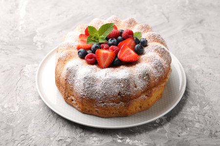 Tasty Bundt cake with powdered sugar and berries