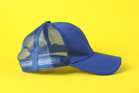 One blue baseball cap on yellow background, closeup. Mockup for design