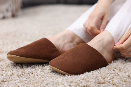 Woman in brown slippers on soft beige carpet at home, closeupのeditorial素材